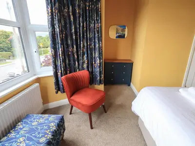 a bedroom with a red chair and a window at Limhus House in Keswick