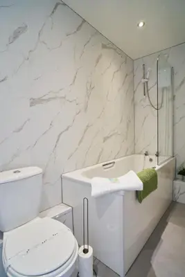 a white bathroom with a toilet and a bath tub at 1 BDR Apt By Caledonia Luxe Stays Short Lets & Serviced Accommodation Lanark in Douglas