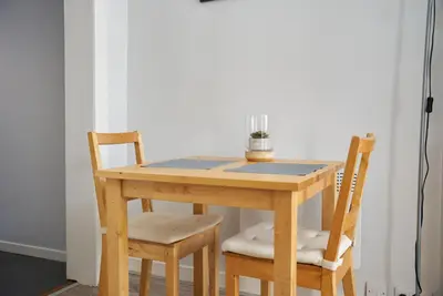 a wooden table with two chairs and a table with a plant on it at 1 BDR House By Caledonia Luxe Stays Short Lets & Serviced Accommodation Lanark in Douglas