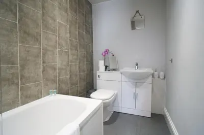 a bathroom with a tub and a toilet and a sink at 1 BDR House By Caledonia Luxe Stays Short Lets & Serviced Accommodation Lanark in Douglas