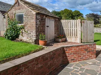 a brick house with a fence in a yard at Rivendell in Burgh by Sands