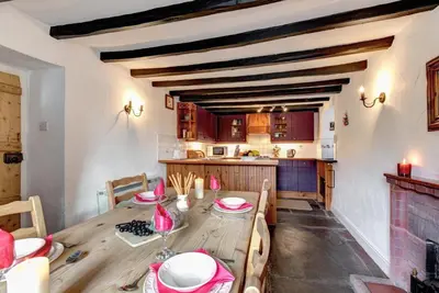 a dining room with a wooden table with chairs and a kitchen at 2 Bed in Elterwater oc-gl004 in Chapel Stile