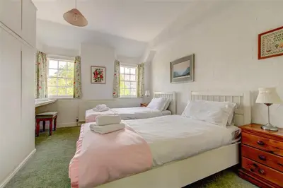 a bedroom with two beds and a dresser and two windows at 5 Bed in Grasmere oc-gl008 in Grasmere