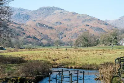 a gate in a field with mountains in the background at 2 Bed in Grasmere oc-gl081 in Grasmere