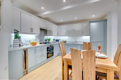 a kitchen with white cabinets and a wooden table and chairs at 2 Bed in Portinscale oc-gl129 in Portinscale