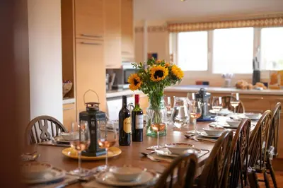 a table with glasses and a vase of flowers and wine bottles at 6 Bed in Keswick oc-ld177 in Keswick