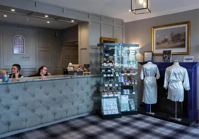 a man and a woman sitting at a bar in a store at Gretna Hall Hotel in Gretna Green