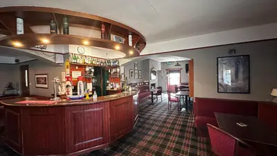 a bar in a pub with a bar counter at The Bruce Hotel in Newton Stewart