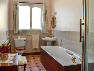a bathroom with a tub and a toilet and a sink at Rose Rigg Cottage in Kirklinton