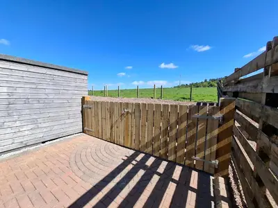 a wooden fence next to a brick patio at Cairnyard Lodges - Woodrow in Beeswing