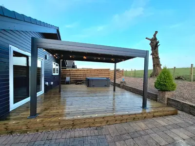 a covered deck with a grill on a house at Cairnyard Lodges - Woodside in Beeswing