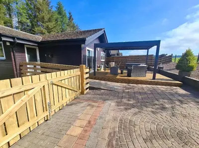 a backyard with a wooden fence and a pavilion at Cairnyard Lodges - Woodside in Beeswing