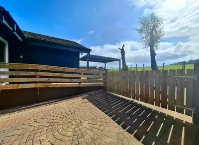 a wooden fence with a bench in front of a building at Cairnyard Lodges - Woodside in Beeswing