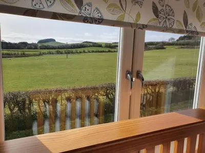 a window with a view of a green field at Strathken Cottage in Castle Douglas