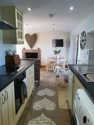 a kitchen with a table and a dining room at Strathken Cottage in Castle Douglas