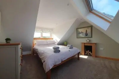 a bedroom with a bed and a fireplace in a attic at Strathken Cottage in Castle Douglas