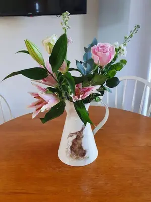 a white vase filled with flowers on a table at Strathken Cottage in Castle Douglas