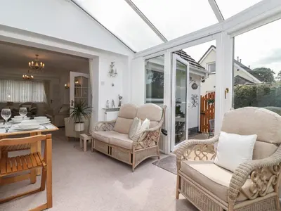 a conservatory with wicker chairs and a table at Oaklea in Keswick