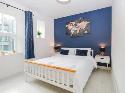 a bedroom with a white bed and a blue wall at 8A Corkickle in Whitehaven