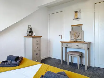 a bedroom with a bed and a desk with a mirror at Squirrel Lodge in Keswick