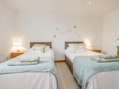 a bedroom with two twin beds with blue sheets at Shundraw Cottage in Keswick