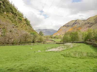 a field of green grass with mountains in the background at Shundraw Cottage in Keswick