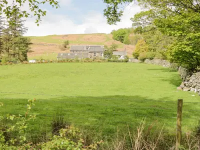 a large green field with a house in the background at Shundraw Cottage in Keswick