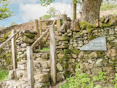 a stone wall with a sign that says park to st louis church at Shundraw Cottage in Keswick