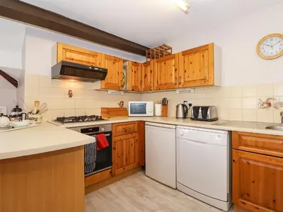 a kitchen with wooden cabinets and white appliances at Bakers Yard Cottage in Ambleside
