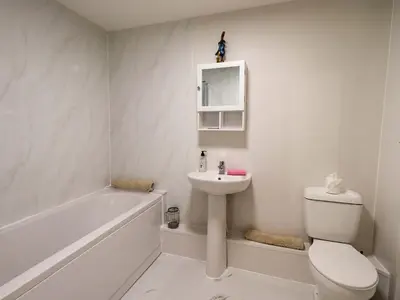 a white bathroom with a toilet and a sink at Bakers Yard Cottage in Ambleside