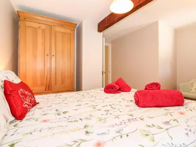 a bedroom with a bed with red pillows on it at Bakers Yard Cottage in Ambleside
