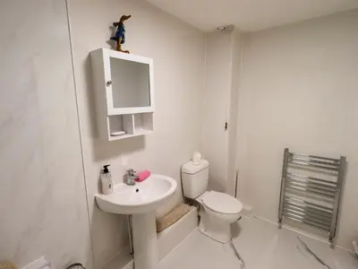 a white bathroom with a toilet and a sink at Bakers Yard Cottage in Ambleside