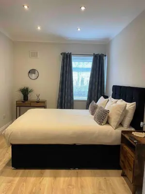 a bedroom with a large bed with a window at Lovely 2 bed apartment with hot tub log burner and off street parking in Dumfries