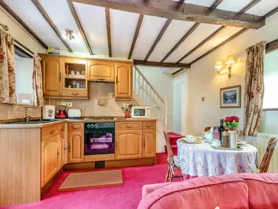 a kitchen with wooden cabinets and a table at Rose Cottage - Lpd in Ireby