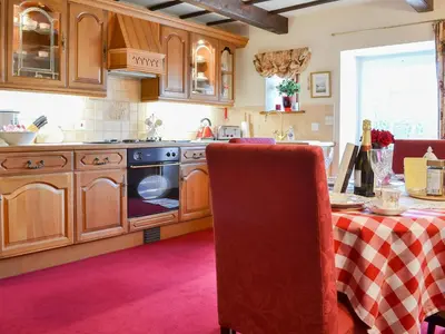 a kitchen with wooden cabinets and a table with a table cloth at Rosedale- Lyl in Ireby