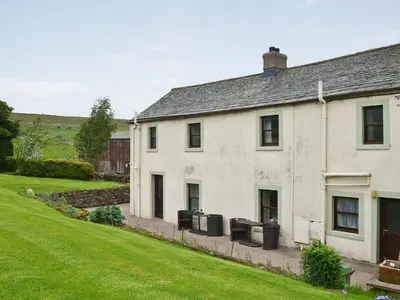 a white house with trash cans in front of it at Ellarbeck Cottage in Caldbeck