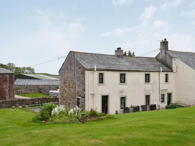 an old stone house with a grass yard at Swaledale Cottag in Caldbeck
