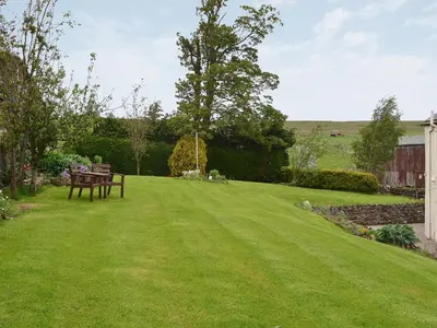 a lawn with a picnic table in a yard at Swaledale Cottag in Caldbeck