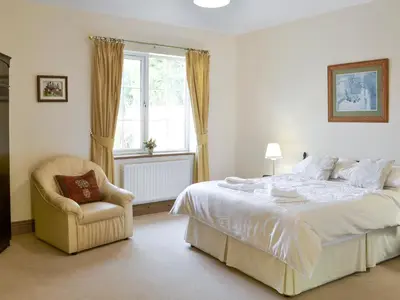 a bedroom with a bed and a chair and a window at Alby Bungalow in Wetheral