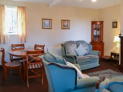 a living room with blue chairs and a table at The Coach House in Wetheral