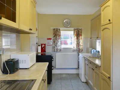 a kitchen with yellow cabinets and a clock on the wall at The Coach House in Wetheral