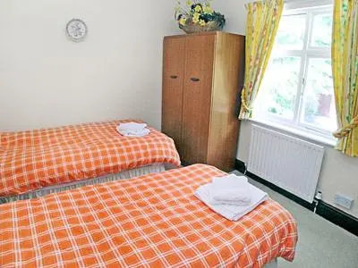 a bedroom with a orange bed and a window at The Coach House in Wetheral