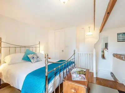 a bedroom with a bed with blue sheets and a table at Hollow Creek Cottage - 28012 in Rockcliffe