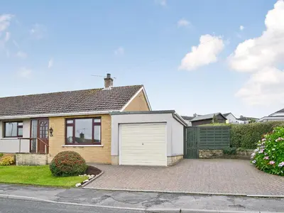 a house with a white garage on a street at Briar Bank Bungalow in Cockermouth