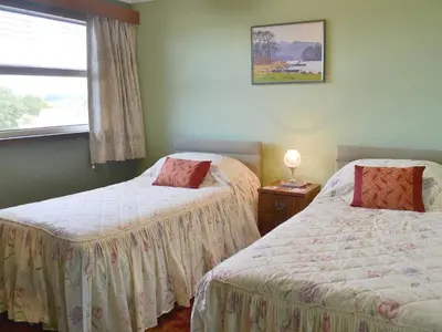 a bedroom with two beds and a window at Briar Bank Bungalow in Cockermouth