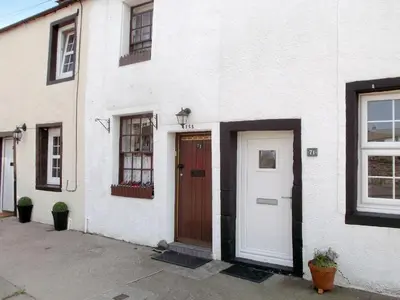 a white house with a brown door and a white door at Tanner's Cottage in Cockermouth