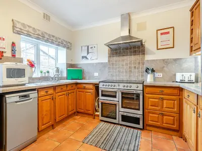 a kitchen with wooden cabinets and a stove top oven at Halls Bank Farm in Plumbland