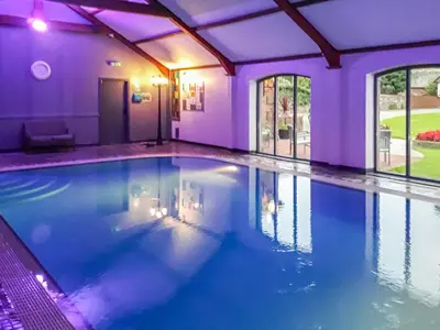 a large swimming pool in a house with purple lighting at Beckside in Gilcrux