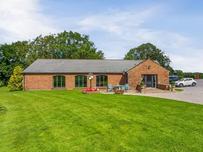 a brick building with a lawn in front of it at Beckside in Gilcrux