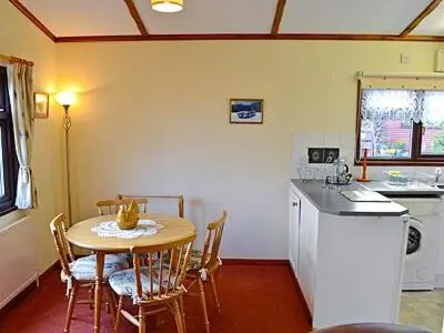a kitchen with a table and chairs and a kitchen with a sink at Rosella in Bridekirk